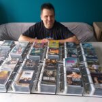 ulotki filmowe kolekcja. Mężczyzna siedzący przed segregatorami ze zbiorami ulotek