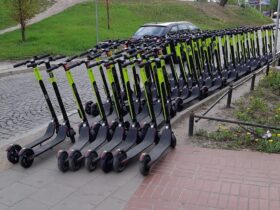 Bardzo dużo hulajnóg stojących na całej szerokości chodnika.