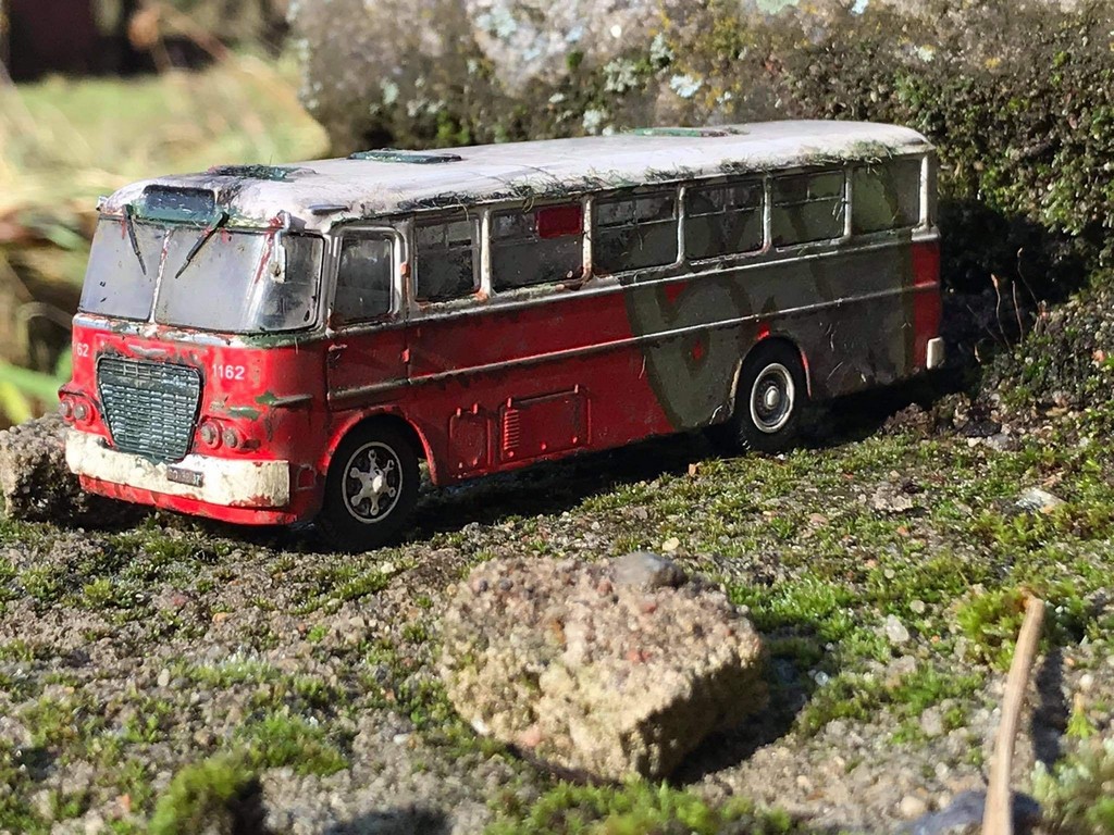 Miniaturowy autobus ustawiony na kamieniu.