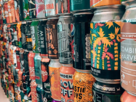 W rzędach ustawione puszki w różnych kolorach i wzorach.