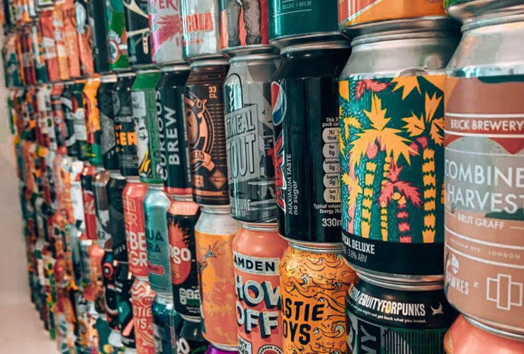 W rzędach ustawione puszki w różnych kolorach i wzorach.