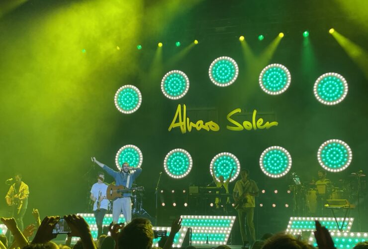 Na scenie stoi artysta wraz z zespołem. W ręku trzyma mikrofon. W tle napis: Alvaro Soler.