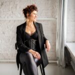 Ola braffierka siedzi na krześle ubrana w czarny strój.