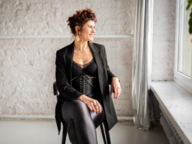 Ola braffierka siedzi na krześle ubrana w czarny strój.