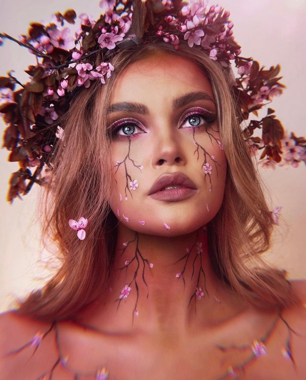 Painterka w makijażu z motywem kwiatków. Na głowie ma wianek