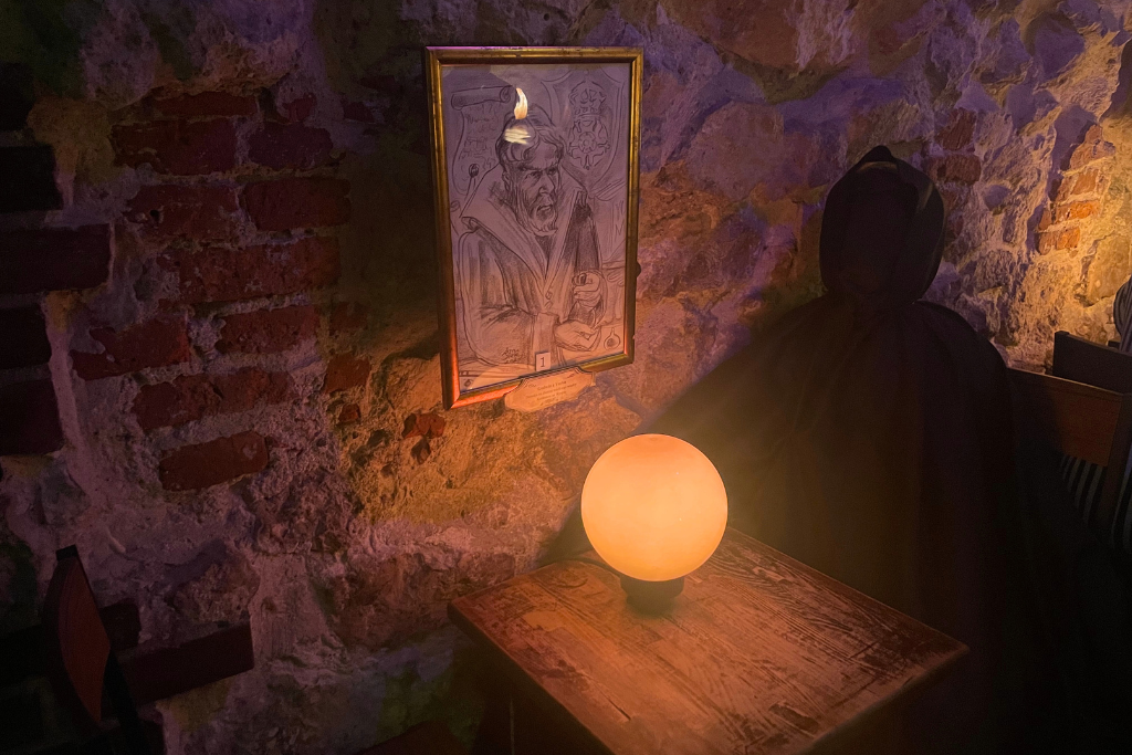 Dziurawy kocioł w Krakowie. Kawiarnia w stylu Harrego Pottera, przy stoliku siedzi czarna postać - Dementor.