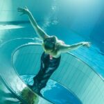 Kobieta płynąca w syrenim ogonie w basenie, czyli mermaiding