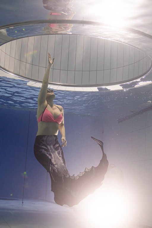 Kobieta płynąca w syrenim ogonie w basenie