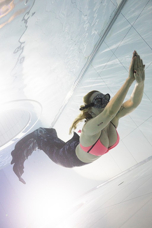 Kobieta płynąca w syrenim ogonie w basenie, czyli mermaiding