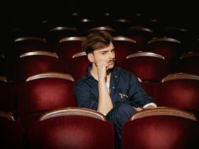 Wiktor Dyduła na planie teledysku Koło Fortuny. Siedzi na sali teatralnej.