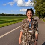 Ola przewodniczka po Krakowie - akcent krakowski stoi na chodniku. W tle zielone pole.