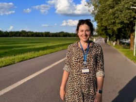 Ola przewodniczka po Krakowie - akcent krakowski stoi na chodniku. W tle zielone pole.