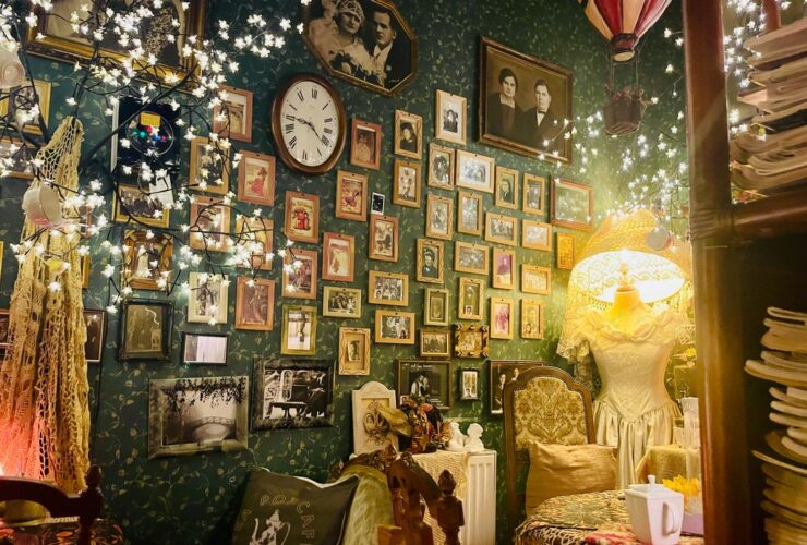 Wnętrze Herbaciarni Niebieskie Migdały, niskie stoliki, przy których stoją fotele. Na ścianie wiszą niewielkie ramki z fotografiami. W prawym rogu stoi wysoka lampa, kształtem przypominająca ludzką sylwetkę, ubraną w sukienkę.