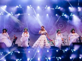 Kobiety występujące na scenie, ubrane są w długie białe suknie.