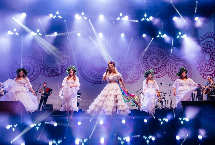 Kobiety występujące na scenie, ubrane są w długie białe suknie.