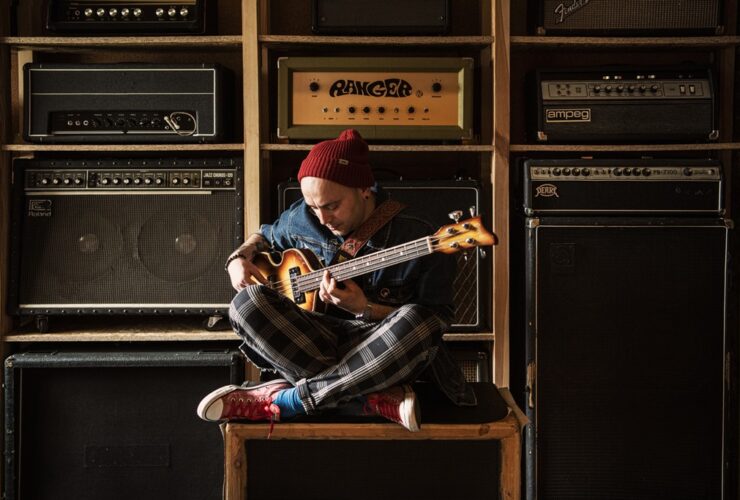 Damian Sikorski siedzi na głośniku z gitarą